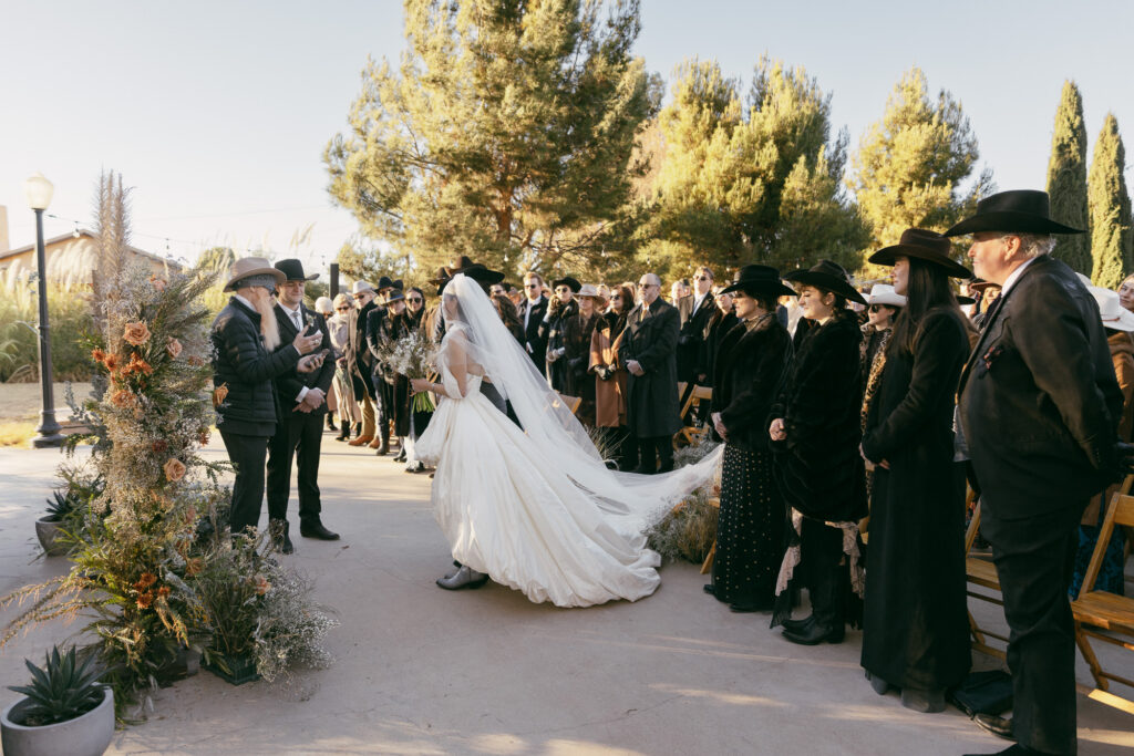 Bride walking down the aisle at The Gage Hotel in Marathon, Texas, surrounded by wedding guests.